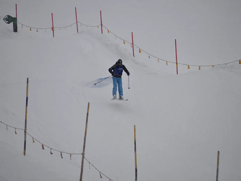 Skifahrer auf einer Piste zwischen Absperrstangen.
